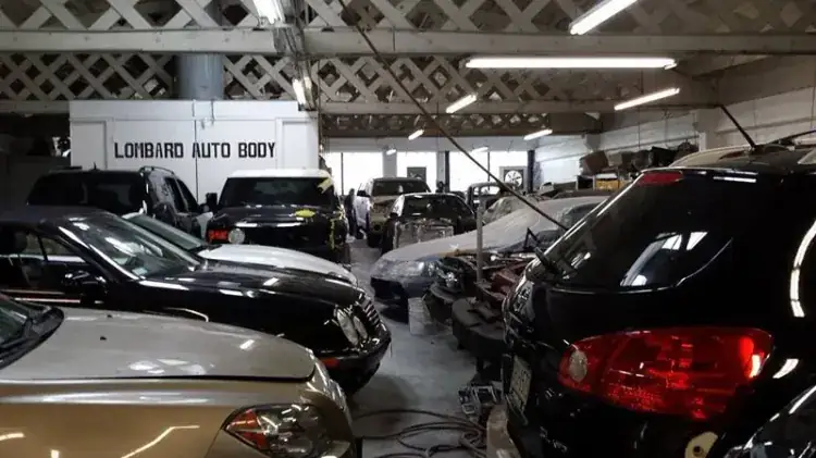 Inside Lombard Auto Body at 2340 Lombard Street — customer vehicles in the shop bays beneath the painted LOMBARD AUTO BODY wall sign