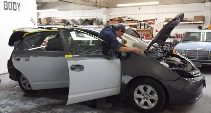 Technician masking a vehicle for paint prep at Lombard Auto Body in San Francisco